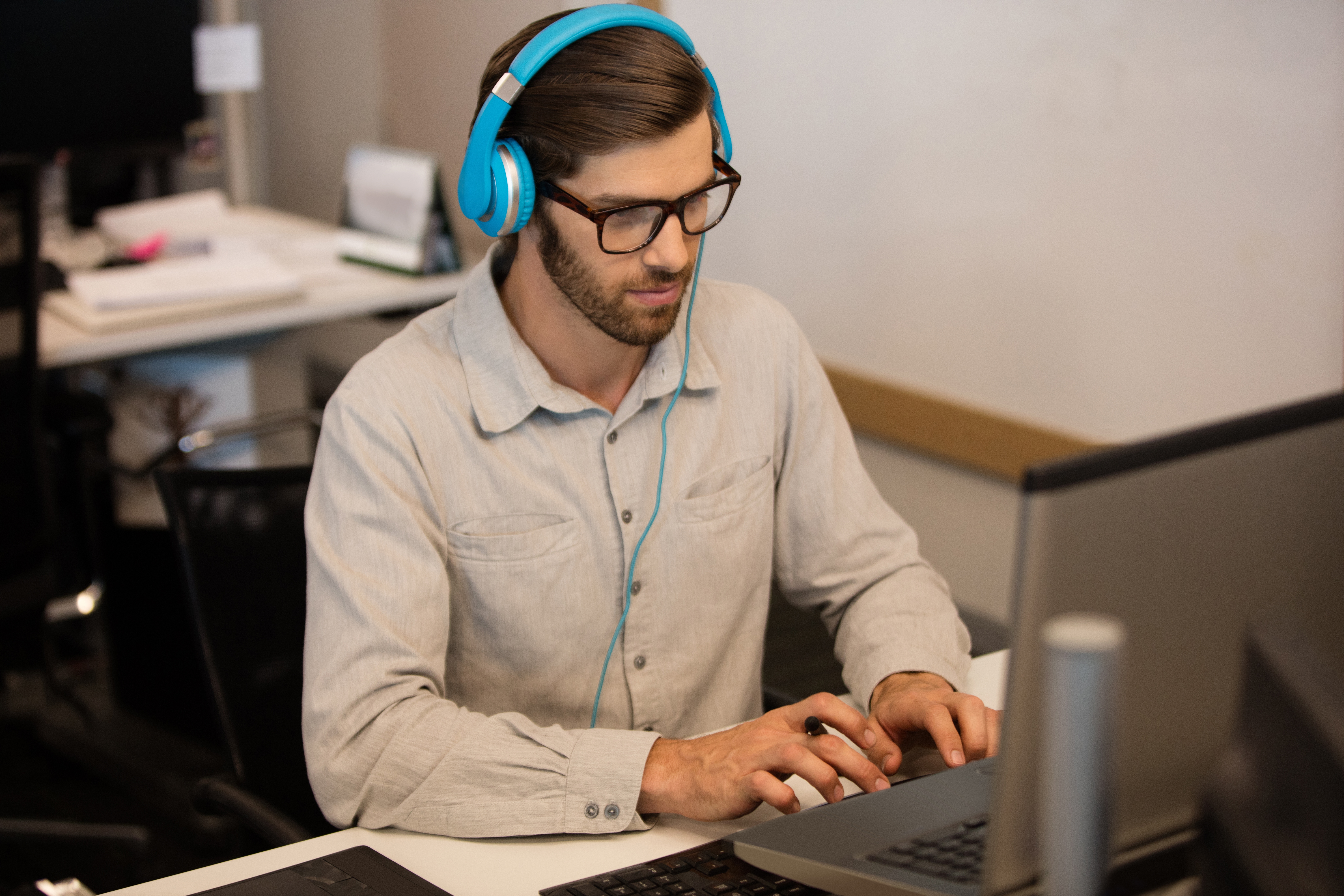 Man wearing blue headphones working at a computer